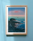 Framed Japanese Art Poster by Kawase Hasui capturing the ocean and rocks at dawn, with pink sky and crashing whitecaps.